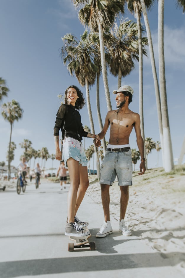 couple longboarding near beach