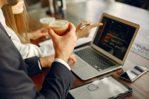 man working on laptop with coffee in hand